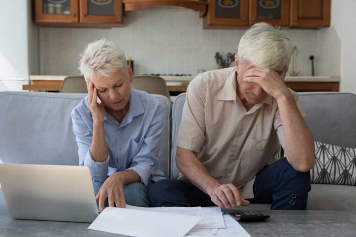 Senior couple looking stressed while reviewing financial documents at home