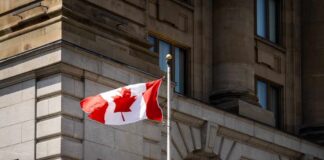 Canadian flag waving in front of a stone building