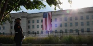 A Marine standing guard in front of the Pentagon with an American flag in the background