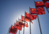 Beijing’s New AI System Raises Big Questions Multiple Chinese flags waving against a clear blue sky