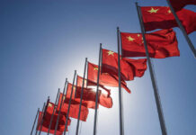 Beijing’s New AI System Raises Big Questions Multiple Chinese flags waving against a clear blue sky