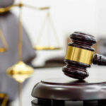 Justice Denied? Death Penalty Dropped A wooden gavel resting on a sound block with a blurred scale of justice in the background