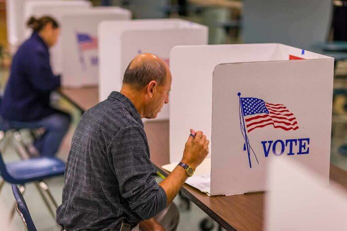 shutterstock_1046168680-1 Man filling out ballot at voting booth