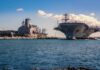 The Race To Rebuild America’s Navy Accelerates Aircraft carrier and support ships docked at a naval harbor