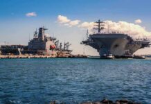 The Race To Rebuild America’s Navy Accelerates Aircraft carrier and support ships docked at a naval harbor