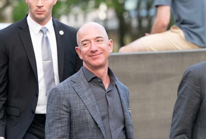 bald man in a gray suit smiling outdoors