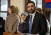 State Department Halts Iran City Hall Meeting Man in suit speaking at a podium with people standing behind
