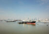 Cargo ship docked in harbor with city skyline in background