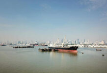 Cargo ship docked in harbor with city skyline in background