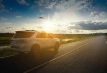 White SUV parked on a rural road at sunset