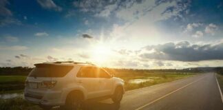White SUV parked on a rural road at sunset