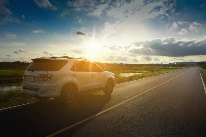 White SUV parked on a rural road at sunset