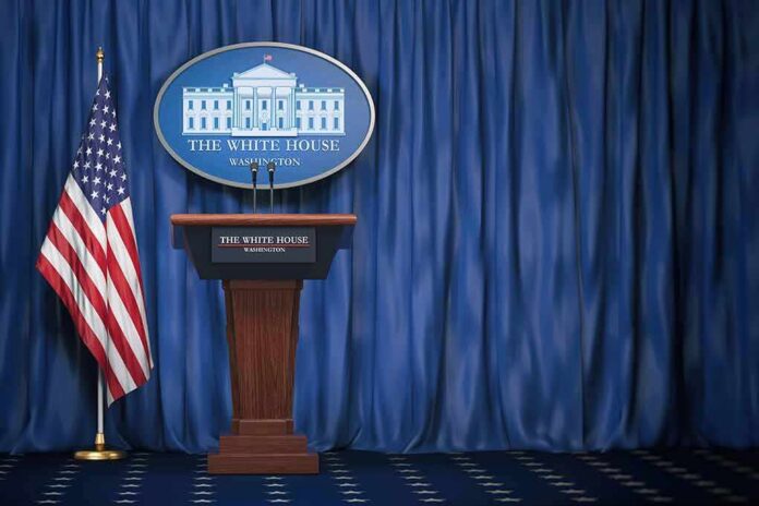 shutterstock_1165119412 White House press briefing podium with U.S. flag and blue curtain