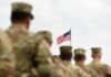 U.S. flag flying above a formation of soldiers in uniform