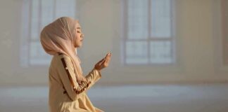 Woman in hijab praying on a mat indoors