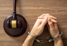 Handcuffed hands beside a judge's gavel