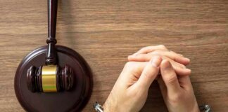 Handcuffed hands beside a judge's gavel