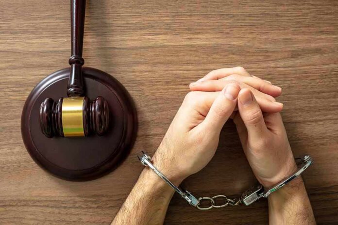 Handcuffed hands beside a judge's gavel