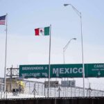 Border crossing with U.S. and Mexico flags and a sign welcoming to Mexico