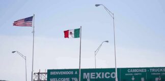 Border crossing with U.S. and Mexico flags and a sign welcoming to Mexico