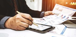 Businessperson analyzing charts with tablet and papers
