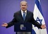 man in suit speaking at a podium with Israeli flag