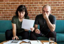 Two adults on a sofa reviewing bills and using a calculator
