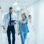 Seconds Turned Celebration Into Unspeakable Tragedy Doctor and nurse walking in a hospital corridor reviewing a tablet