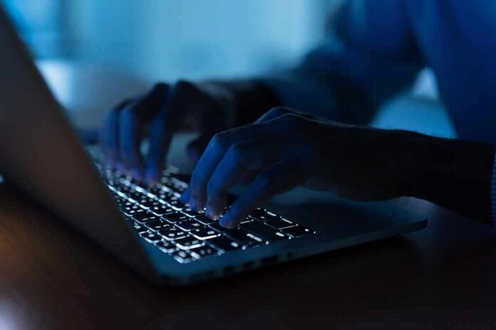 Hands typing on a backlit laptop keyboard at night