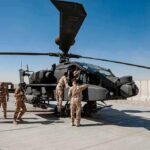 Soldiers inspect a military attack helicopter on a tarmac