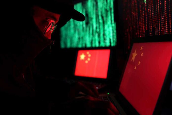 Hooded person using a laptop with Chinese flags on screens