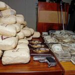 Seized packages, cash, and handguns on a table