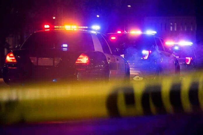 Police cars with flashing lights behind yellow caution tape at night