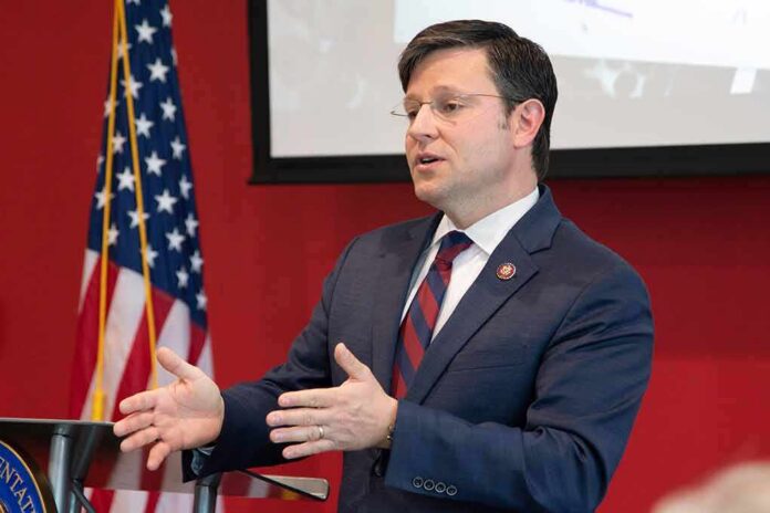 Man in suit speaking at podium with US flag in background