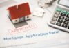Mortgage application form with approved stamp, model house, and calculator