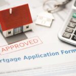 Mortgage application form with approved stamp, model house, and calculator