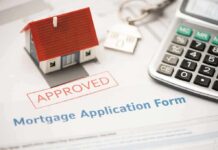 Mortgage application form with approved stamp, model house, and calculator