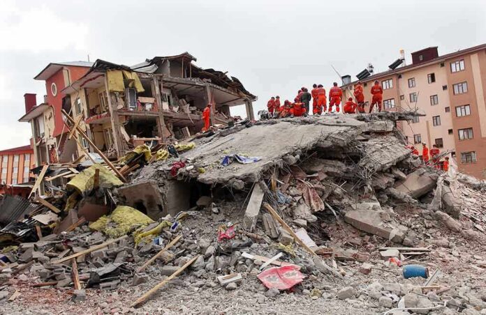 shutterstock_148947701 Rescue workers in orange uniforms on a collapsed building site after an earthquake