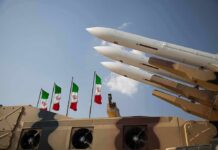 Missile launchers on a military vehicle with flags in the background