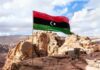 Libya flag waving over rocky desert landscape