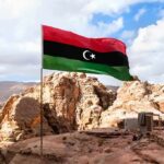 Libya flag waving over rocky desert landscape