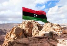 Libya flag waving over rocky desert landscape