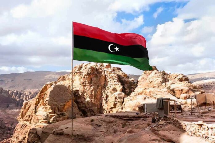 Libya flag waving over rocky desert landscape