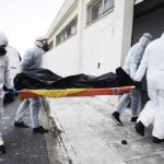 medical team in hazmat suits carrying a body on a stretcher