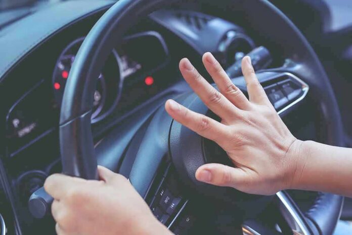 Driver pressing car horn on steering wheel
