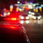 Refusal Charge Explodes Campaign Police car with flashing red lights on a city street at night