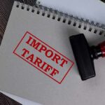 Surprise Tariffs Slammed – Governors Go Nuclear Notebook with import tariff stamp and red-handled rubber stamp