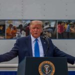 Donald Trump speaks at a podium with arms outstretched