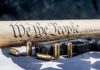 Handgun and bullets on American flag with rolled parchment