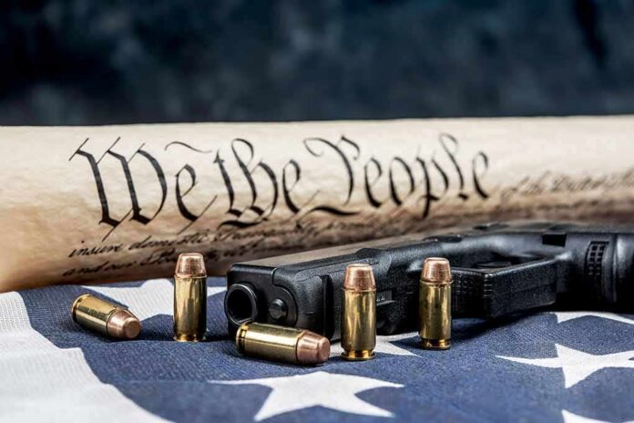 Handgun and bullets on American flag with rolled parchment